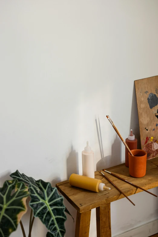 a wooden table topped with art supplies on top of a hard wood floor, a painting, arbeitsrat für kunst, high-quality photo, rituals, banner, studio orange