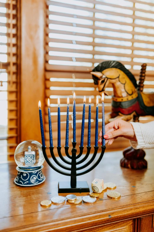 a woman lighting a menorah on a table, by Julia Pishtar, vignette, holiday vibe, well-lit, fan favorite