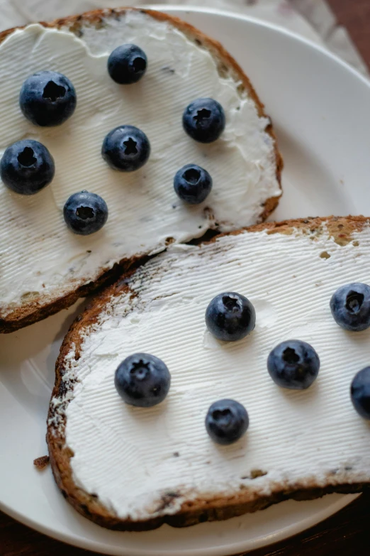 a white plate topped with two pieces of bread covered in cream and blueberries, pexels, white freckles, organic detail, fruit, 6 pack