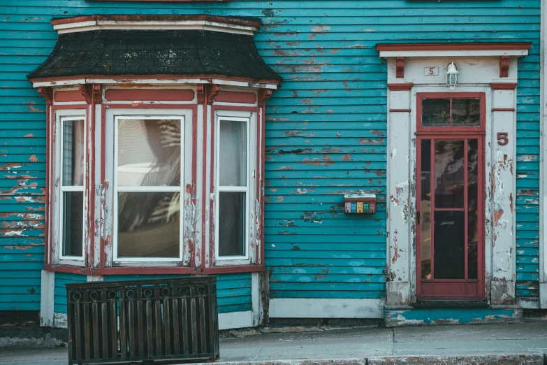 a blue house with a red door and window, inspired by Elsa Bleda, pexels contest winner, maximalism, wooden houses, montreal, faded chipped paint, in a dusty victorian home