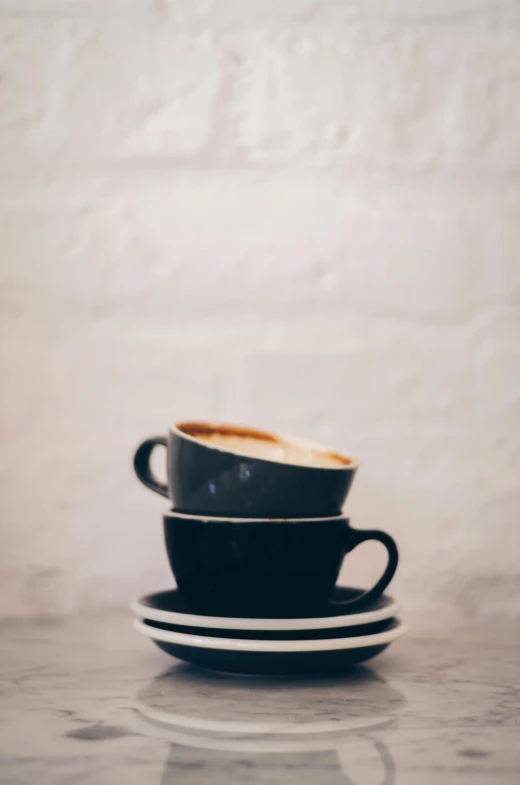 a cup of coffee sitting on top of a saucer, a still life, by Nick Fudge, trending on unsplash, two cups of coffee, multiple stories, stacked image