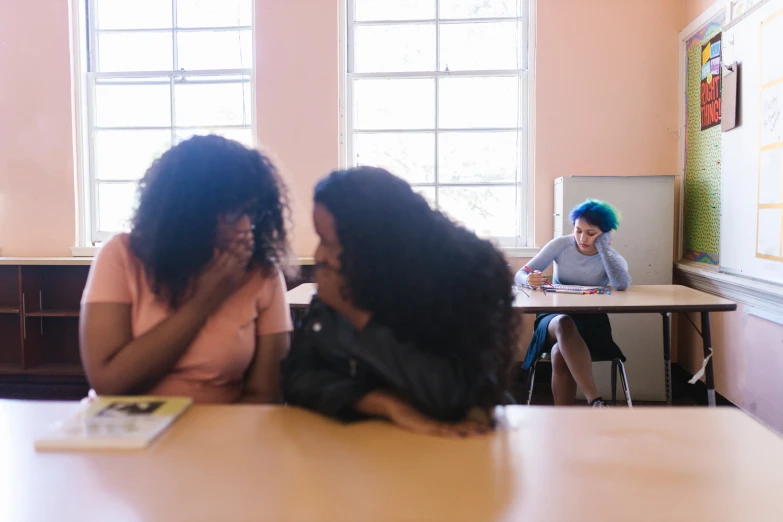two women sitting at a table in a classroom, by Jessie Algie, trending on pexels, people panic in the foreground, ashteroth, half turned around, teenage girl