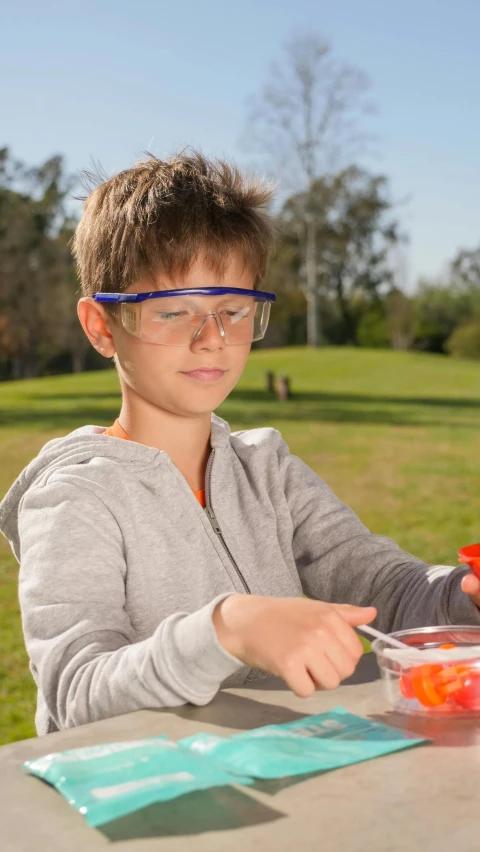 a little boy that is sitting at a table, scientific glassware, outside, thumbnail, sport glasses