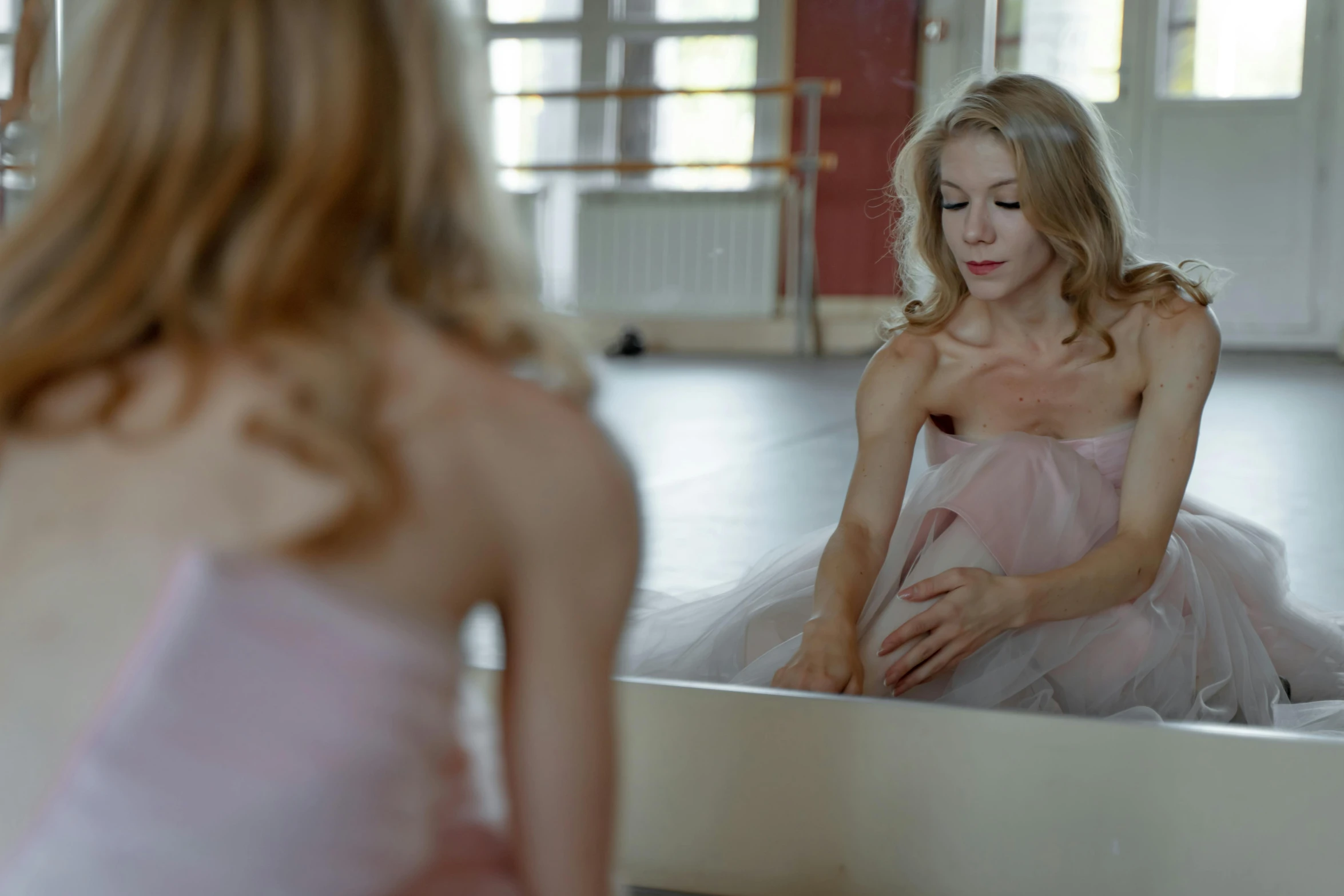 a woman in a pink dress sitting in front of a mirror, by Emma Andijewska, pexels contest winner, arabesque, choreographed, still from the film, pink romantic tutu, sad look