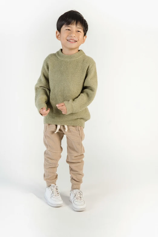 a young boy in a green sweater and khaki pants, in front of white back drop, on textured base; store website, yzy, thumbnail