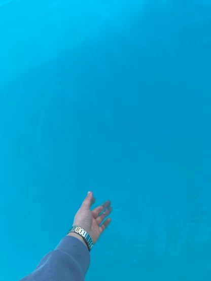 a person reaching for a fish in the water, an album cover, inspired by Yves Klein, unsplash, hurufiyya, poolside, sky - high view, low quality photo, tourist photo