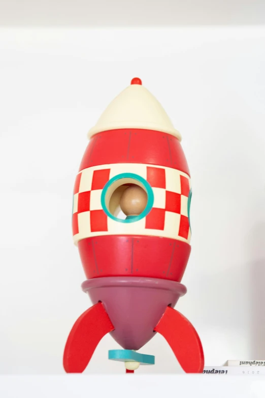 a close up of a toy rocket on a shelf, by Tom Bonson, pop art, mark ryden in the style of, 1970', vostok-1, a wooden