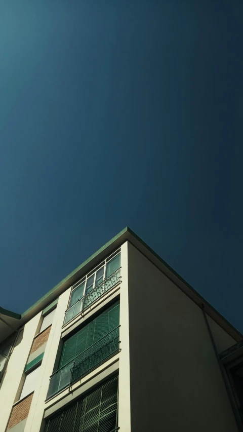 a tall building with a clock on top of it, an album cover, inspired by Leandro Erlich, unsplash, photorealism, green sky, low angle!!!!, minimal structure, residential area
