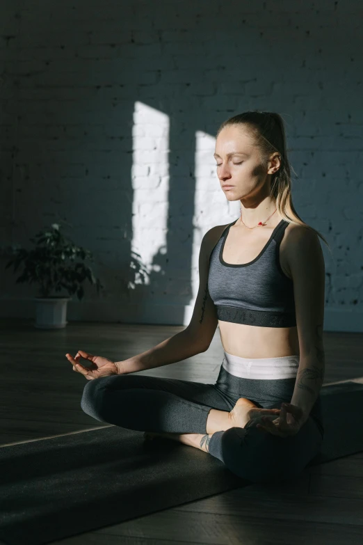 a woman sitting in the middle of a yoga pose, pexels contest winner, light and space, sports clothing, low quality photo, heart rate, paul barson