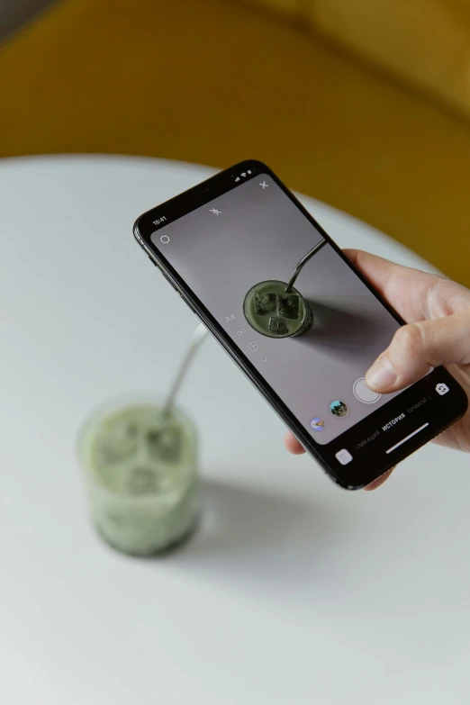 a person taking a picture of a green smoothie, a hologram, by Matthias Stom, mobile learning app prototype, 3d printed, tiktok, detailed product image