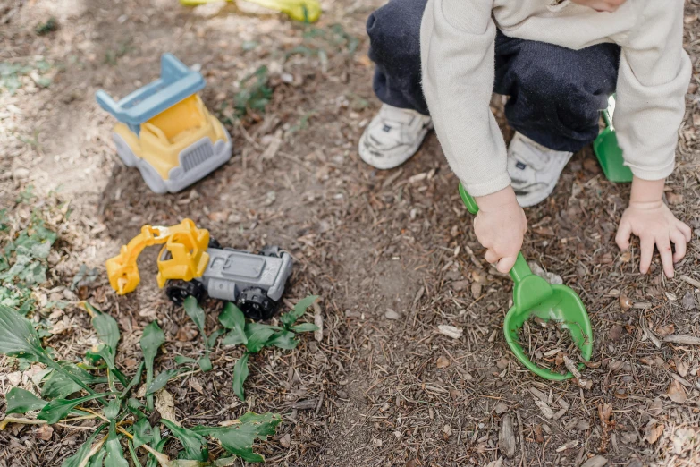 a little boy that is playing in the dirt, holding a yellow toothbrush, scattered props, with a garden, subtle detailing