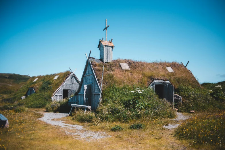 a windmill sitting on top of a grass covered hillside, an album cover, by Jesper Knudsen, pexels contest winner, renaissance, wooden houses, inuit, roof with vegetation, museum photo