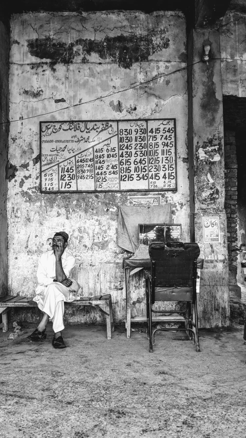 a black and white photo of a man sitting on a chair, by Riza Abbasi, old signs, charts, afar, ap