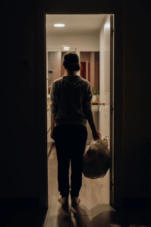 a woman walking into a dark room carrying a bag, pexels, realism, getting groceries, award winning movie still, in the kitchen, lonely human walking