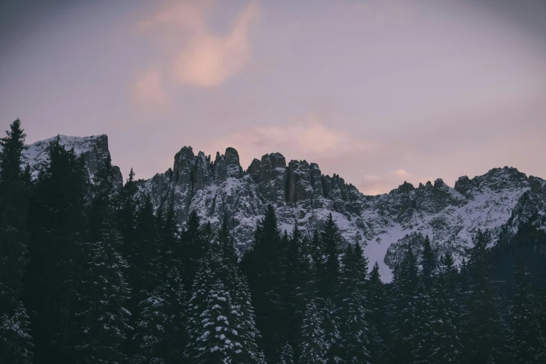 a snow covered mountain with pine trees in the foreground, pexels contest winner, romanticism, cliff side at dusk, tall stone spires, pink hues, grey