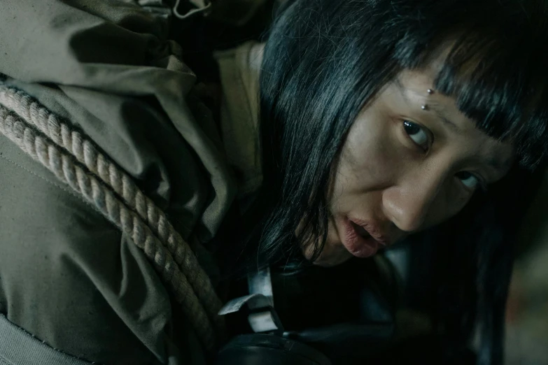 a close up of a person holding a cell phone, an album cover, inspired by Kanō Tan'yū, hurufiyya, wearing ripped dirty flight suit, asian woman, movie action still frame, [ theatrical ]