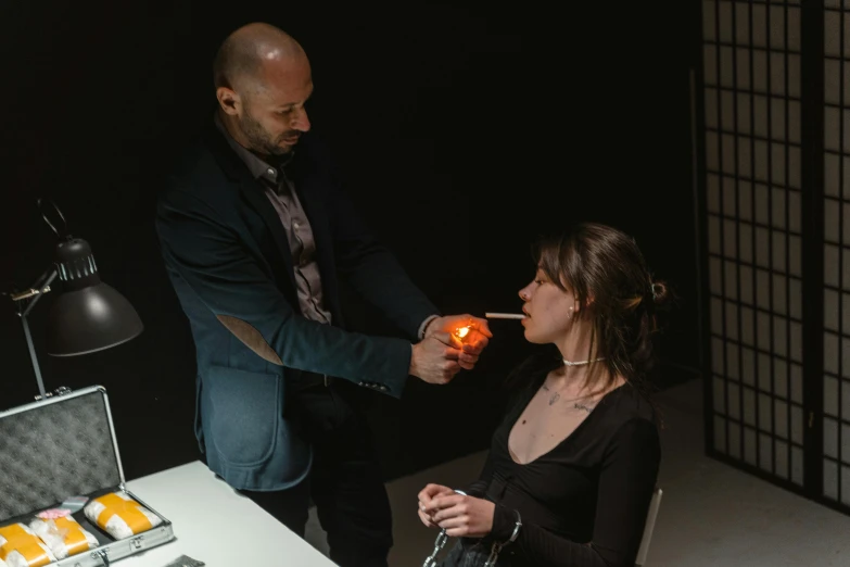 a man putting an orange on a woman's face, by Adam Marczyński, holding a candle holder, in a dark studio room, profile picture, magical potions