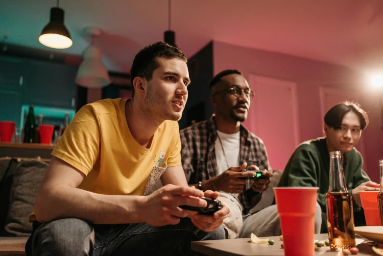 a group of people sitting around a table playing a video game, pexels, college party, lgbtq, avatar image, handsome man