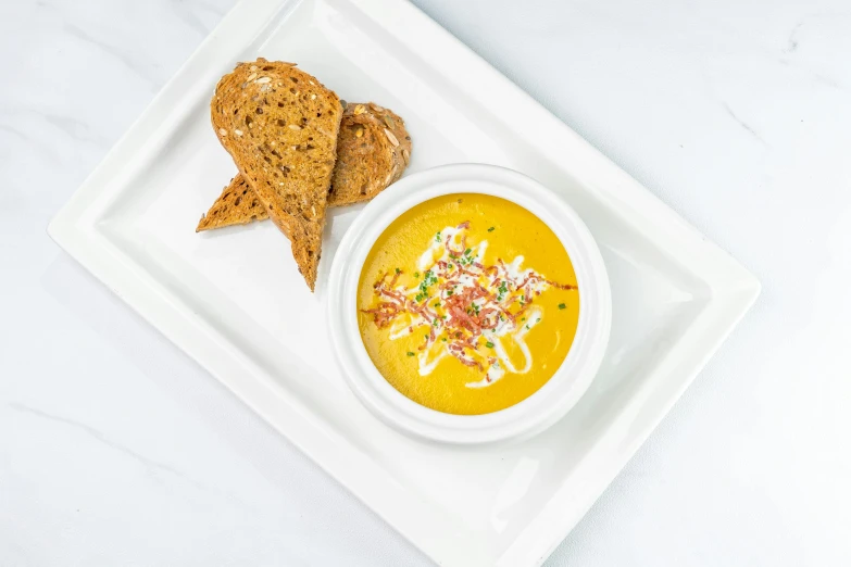 a white plate topped with a bowl of soup next to a piece of bread, vibrant color with gold speckles, chalk, white bg, lumi