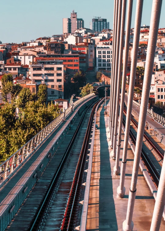 a train traveling through a city next to tall buildings, by irakli nadar, pexels contest winner, art nouveau, bridges and railings, city on a hillside, 4 k cinematic panoramic view, istanbul