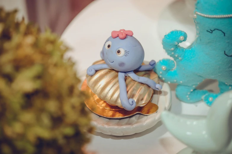 a close up of a cake with an octopus on it, a surrealist sculpture, unsplash, sanrio ornaments, low quality photo, blueish, seashell