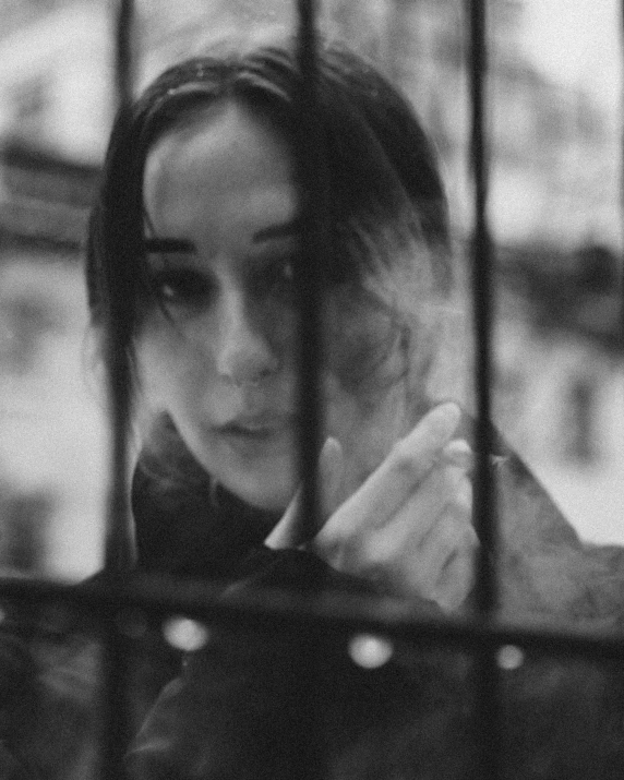 a black and white photo of a woman behind bars, a black and white photo, by Lucia Peka, tumblr, dilraba dilmurat, in a melancholy mood, miro petrov, ((portrait))