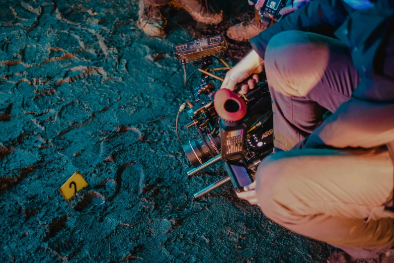 a man sitting on the ground next to a pile of electronics, inspired by roger deakins, pexels contest winner, realism, red camera, murder scene, digging, during the night