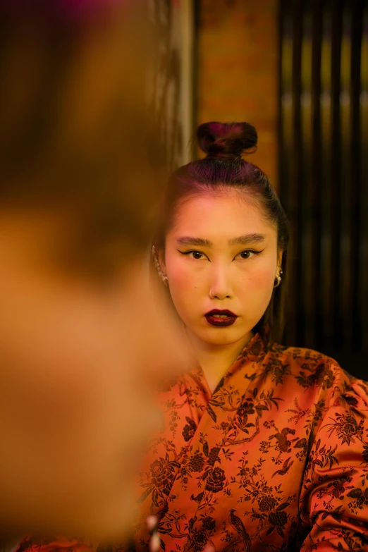 a woman sitting at a table in front of a mirror, an album cover, trending on pexels, ukiyo-e, full face close up portrait, asian man, wearing a velvet robe, non binary model