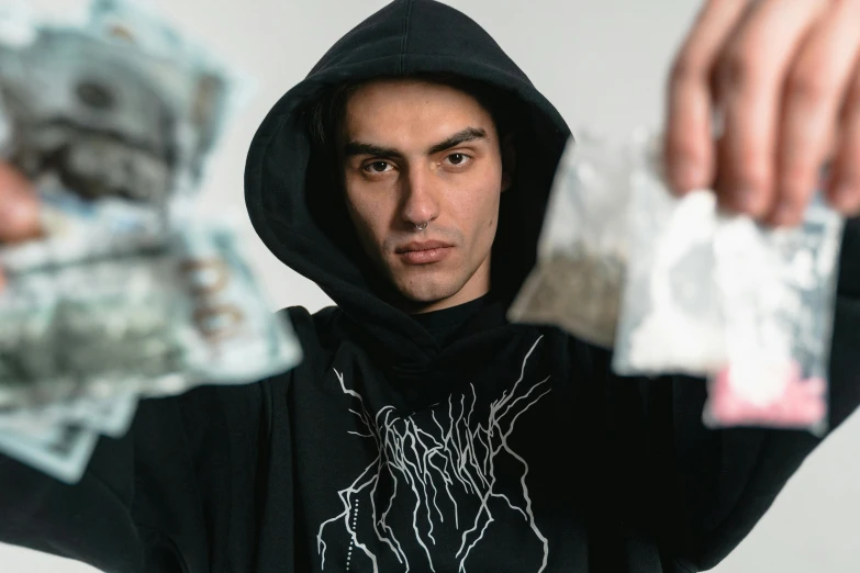 a man in a black hoodie holding a bunch of money, by Daarken, pexels contest winner, hyperrealism, mdma, hasbulla magomedov, wearing a hood with pointy ears, chief keef