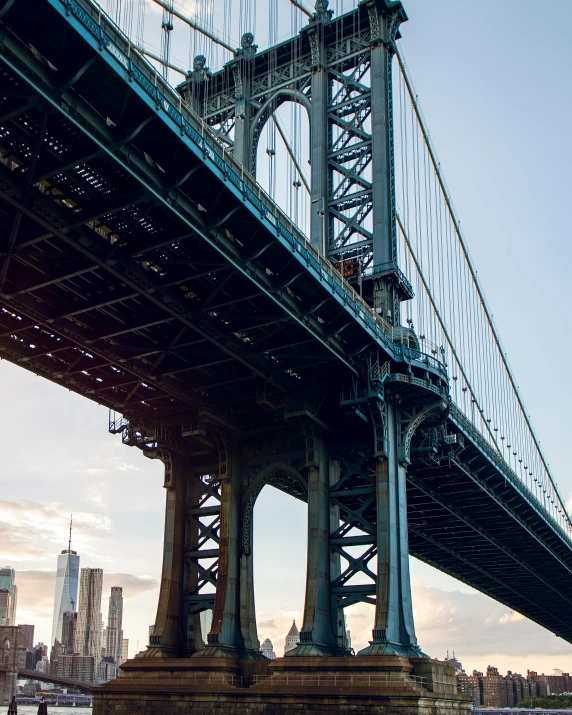 a bridge over a body of water with a city in the background, an album cover, unsplash contest winner, new york buildings, lgbtq, steel archways, 2 0 0 0's photo