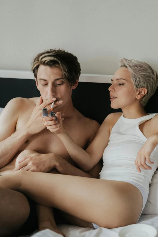 a man and a woman sitting on a bed, by Jessie Alexandra Dick, unsplash contest winner, smoking body, blonde guy, smoking a joint, long boi