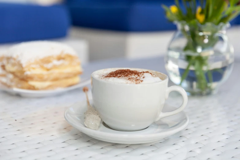 a cup of coffee sitting on top of a white plate, inspired by Richmond Barthé, white travertine terraces, at the terrace, blue, cake