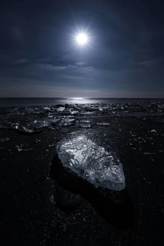 a large piece of ice sitting on top of a beach, by Harald Giersing, moonlight in the darkness, diamonds, today's featured photograph 4 k, 4 k ”