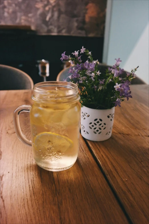 a jar of lemonade sitting on top of a wooden table, a picture, unsplash, renaissance, pretty flowers, is ((drinking a cup of tea)), 2 0 0 0's photo, cafe