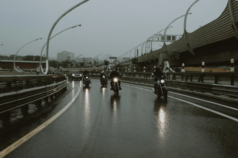 a group of people riding motorcycles down a road, by Adam Marczyński, pexels contest winner, photorealism, rain aesthetic, bridges, extremely gloomy lighting, grey