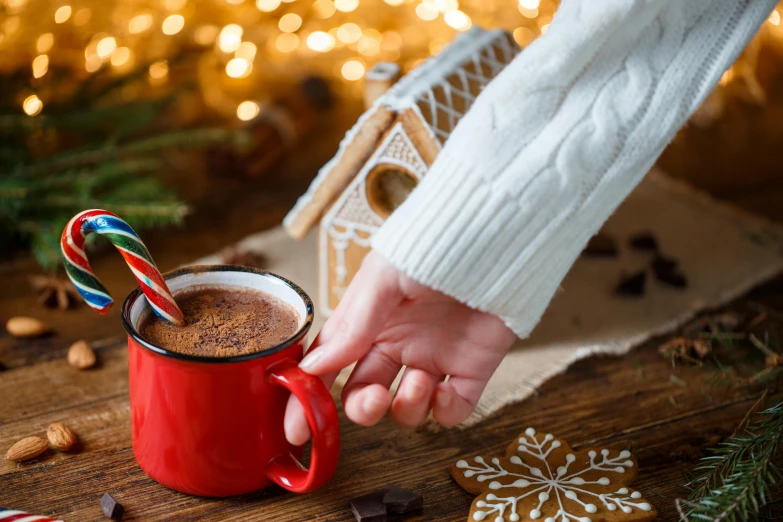 a close up of a person holding a cup of hot chocolate, by Julia Pishtar, pexels contest winner, festive, background image, wooden, santa's workshop