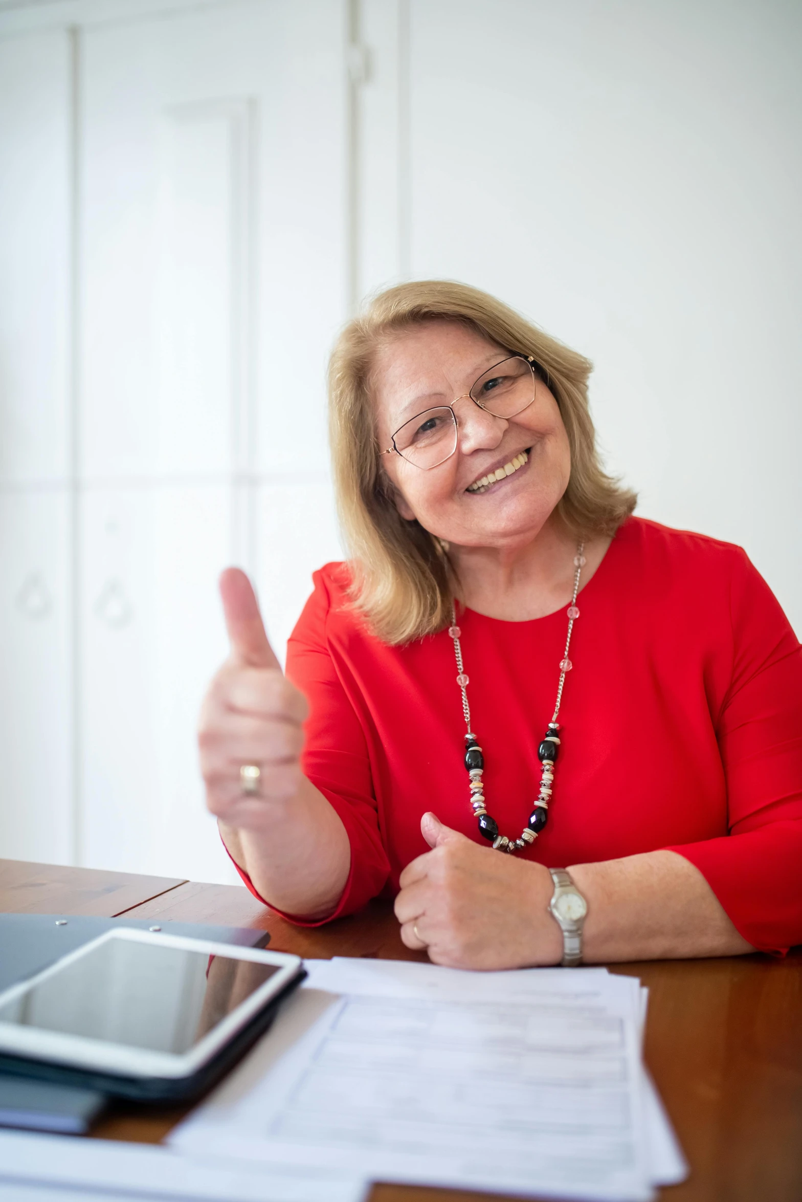 a woman sitting at a table giving a thumbs up, pexels contest winner, mature content, professional profile picture, chilean, document photo