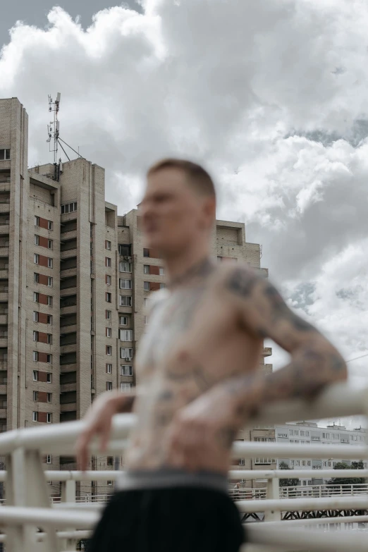 a man standing in front of a tall building, by Joze Ciuha, brutalism, muscular body tattooed, russia in 2 0 2 1, focus in the foreground, slide show