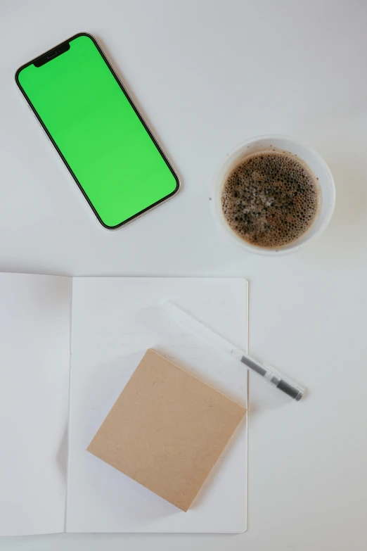 a cell phone sitting on top of a desk next to a cup of coffee, a minimalist painting, trending on pexels, process art, green square, whiteboards, low quality photo, black and green