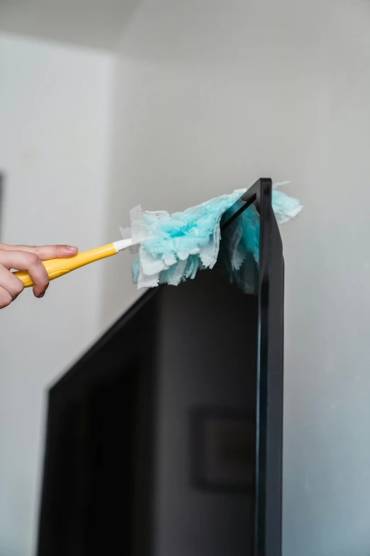 a person cleaning a flat screen tv with a yellow brush, pexels, conceptual art, feathery fluff, plastic wrap, long trunk holding a wand, connectivity