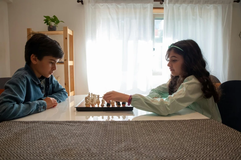 a boy and a girl playing a game of chess, by Harriet Zeitlin, pexels contest winner, hurufiyya, at home, ( side ) profile, yael shelbia, gaming table