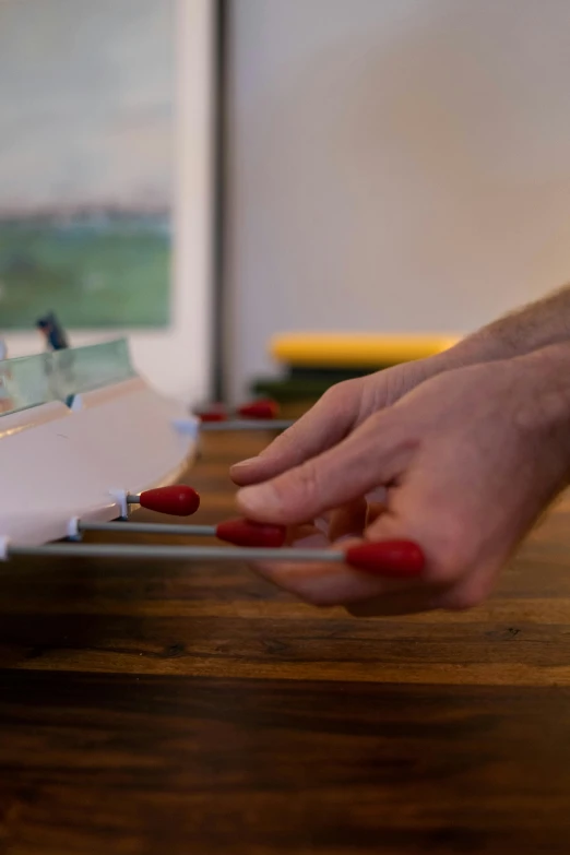 a person using a pair of scissors to cut a piece of paper, an airbrush painting, inspired by Rube Goldberg, unsplash, detailed glowing red implants, still from film, small elongated planes, tabletop model