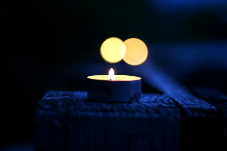 a lit candle sitting on top of a piece of wood, indigo, 5 0 mm bokeh, instagram post, remembrance