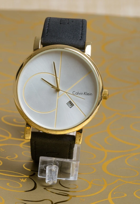 a close up of a wrist watch on a table, an album cover, inspired by Karl Buesgen, unsplash, modernism, white with gold accents, calvin klein, ebay listing thumbnail, 1980s photo