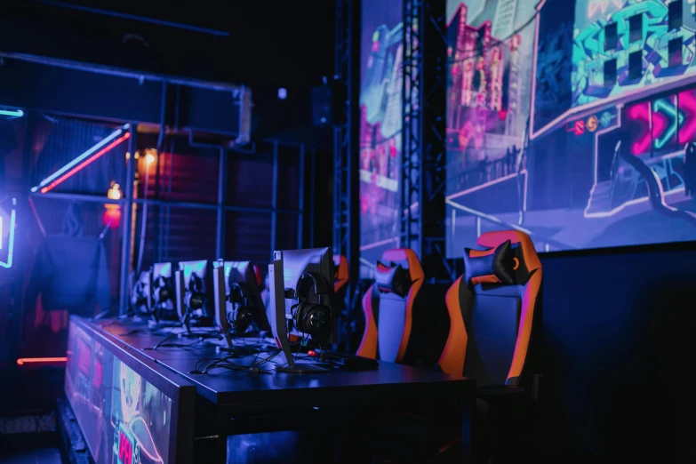 a group of video game controllers sitting on top of a table, softair arena landscape, purple and yellow lighting, with screens and silks, orange and cyan lighting