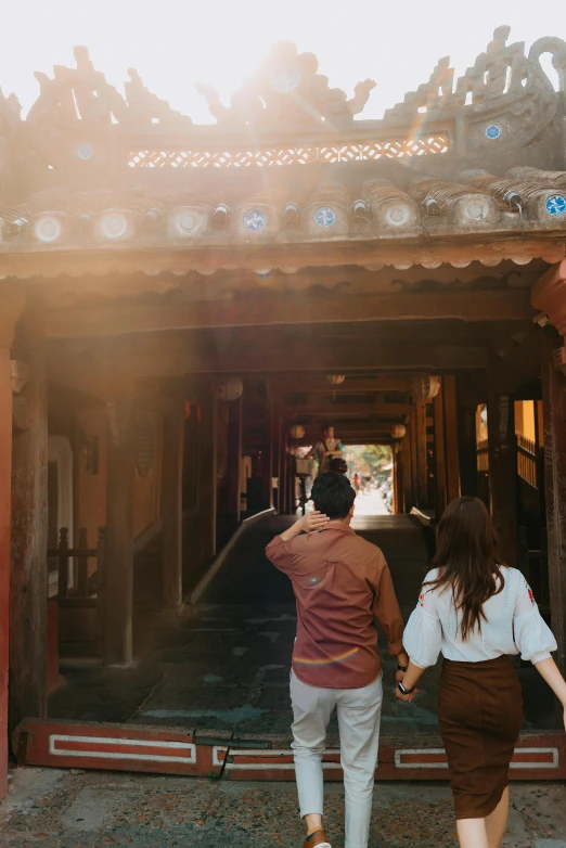 a man and a woman walking in front of a building, pexels contest winner, dreamy chinese town, long hall way, warm hue, back