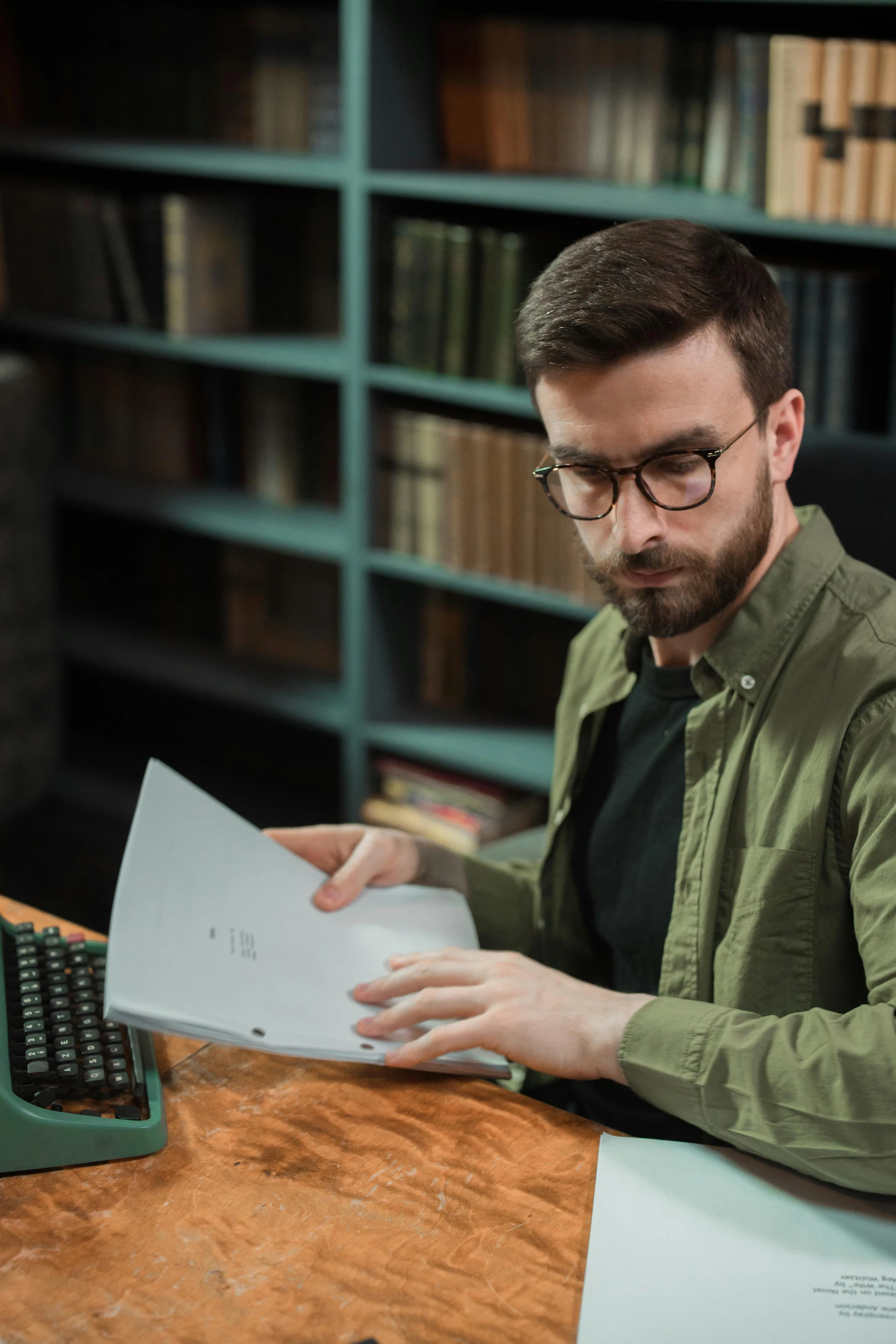 a man sitting at a desk in front of a typewriter, trending on reddit, dynamic angled shot, inspect in inventory image, with square glasses, student