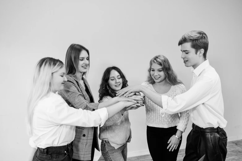 a group of people putting their hands together, a black and white photo, by Emma Andijewska, pexels contest winner, coworkers, casual game, 8k octan advertising photo, posing