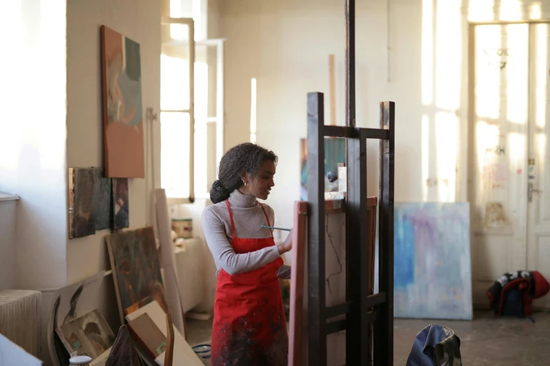 a woman standing in front of a painting easel, pexels contest winner, aida muluneh, in a workshop, 15081959 21121991 01012000 4k, high quality artwork