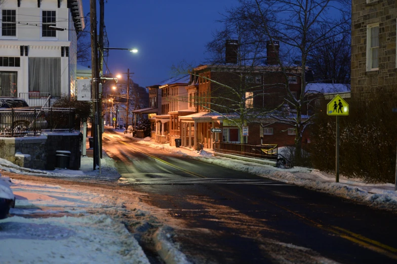 a street filled with lots of snow next to tall buildings, by Carey Morris, pexels contest winner, beautiful small town, late evening, cornell, colonial era street